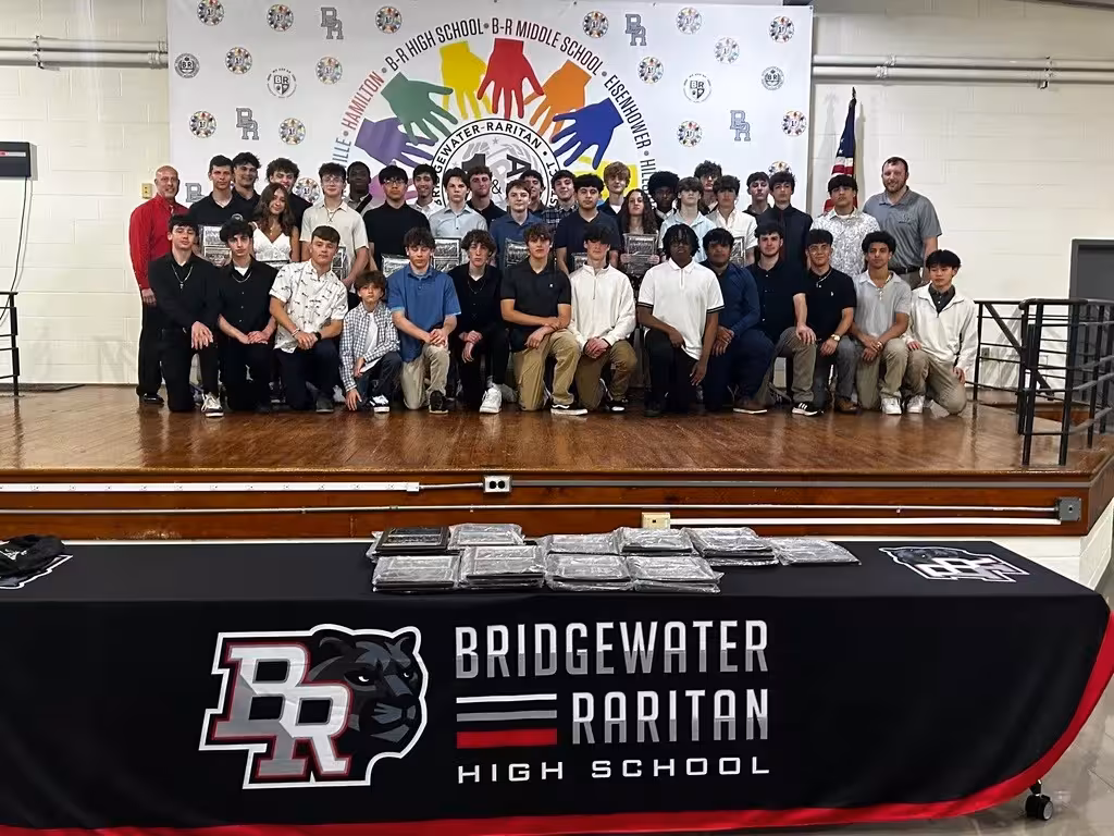 Program celebration photo with branded table throw reading 'BRIDGEWATER RARITAN HIGH SCHOOL' and BR + panther lockup—evidence of event kit and environmental branding in use